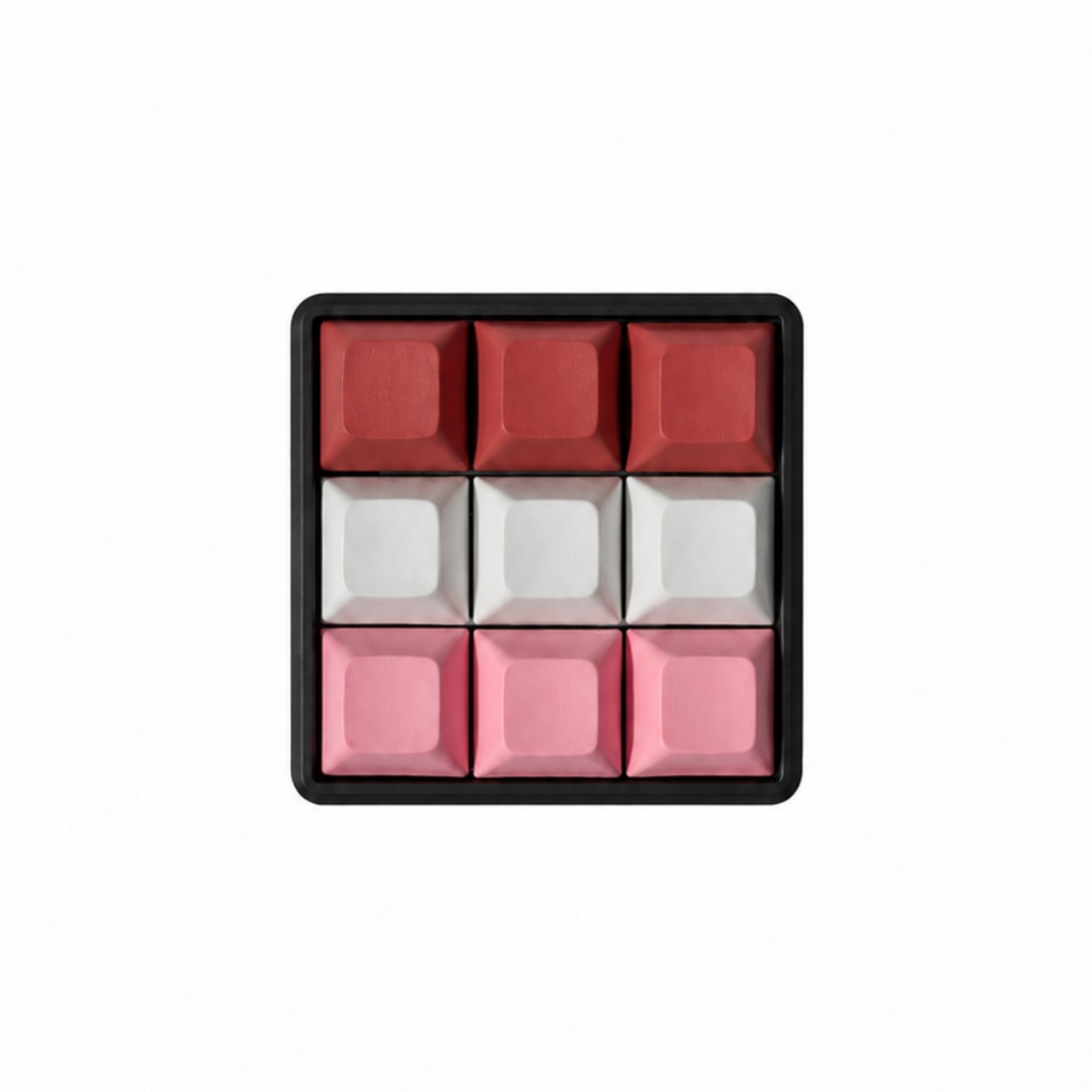The Original 9-key square fidget with terracotta, white, and pink keycaps on a black base.