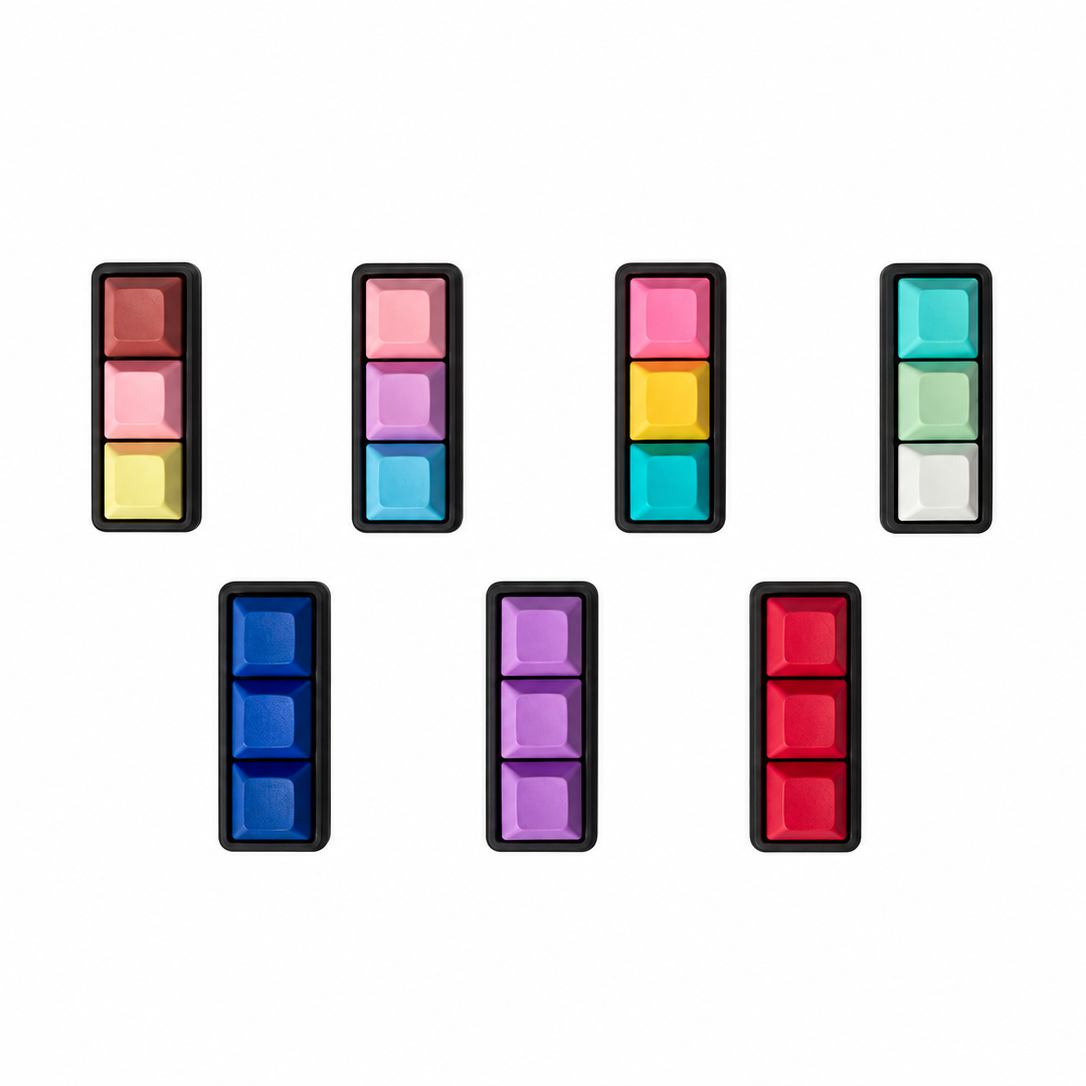 Top view of seven Mini 3-key keyboard fidgets with black bases in Peach Sorbet, Daydream, Electric Splash, Sea Breeze, Blue, Lavender, and Red.
