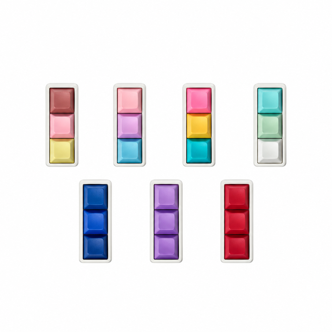 Top view of seven Mini 3-key keyboard fidgets with white bases in Peach Sorbet, Daydream, Electric Splash, Sea Breeze, Blue, Lavender, and Red.