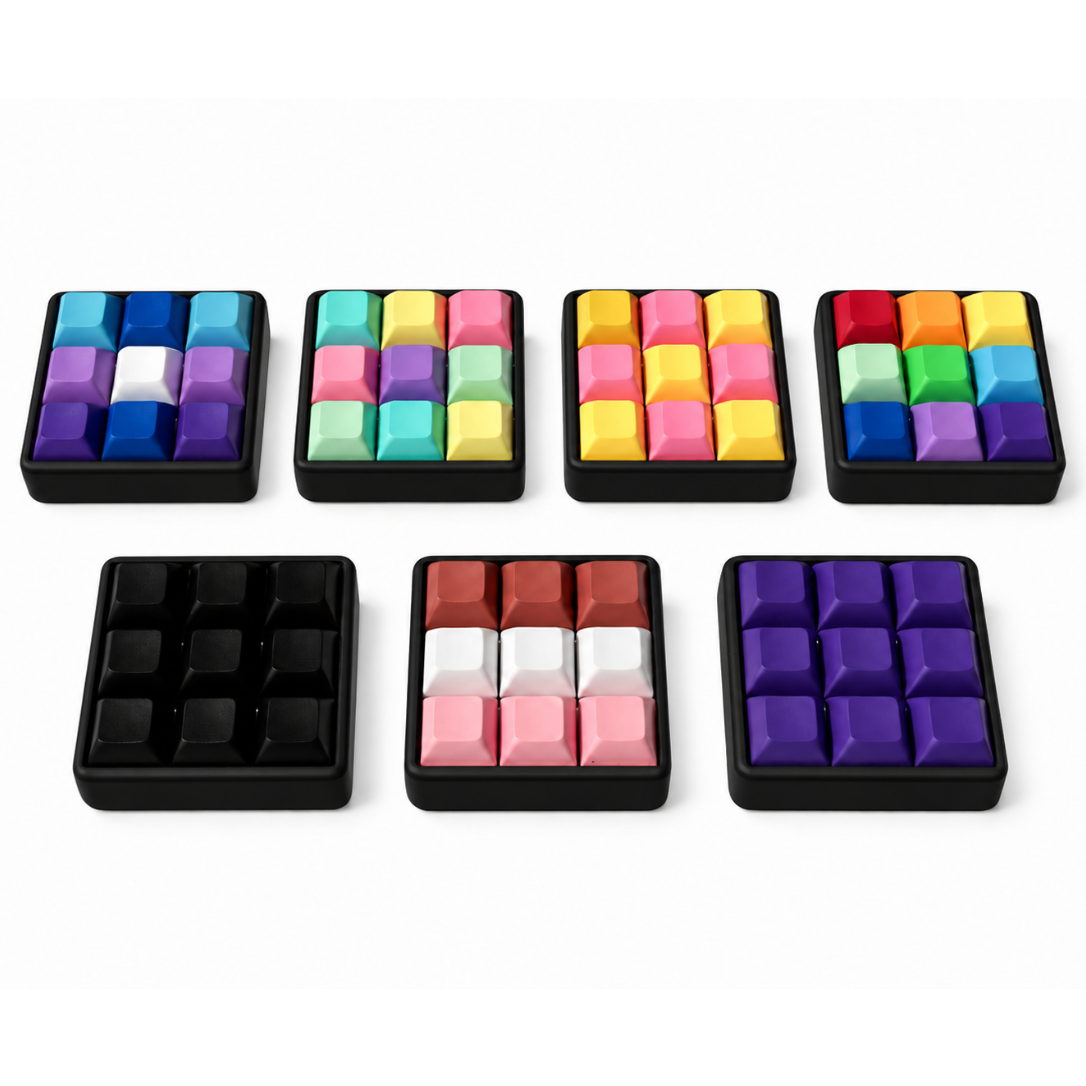Angled view of seven Original 9-key square keyboard fidgets with black bases in different keycap color combinations.
