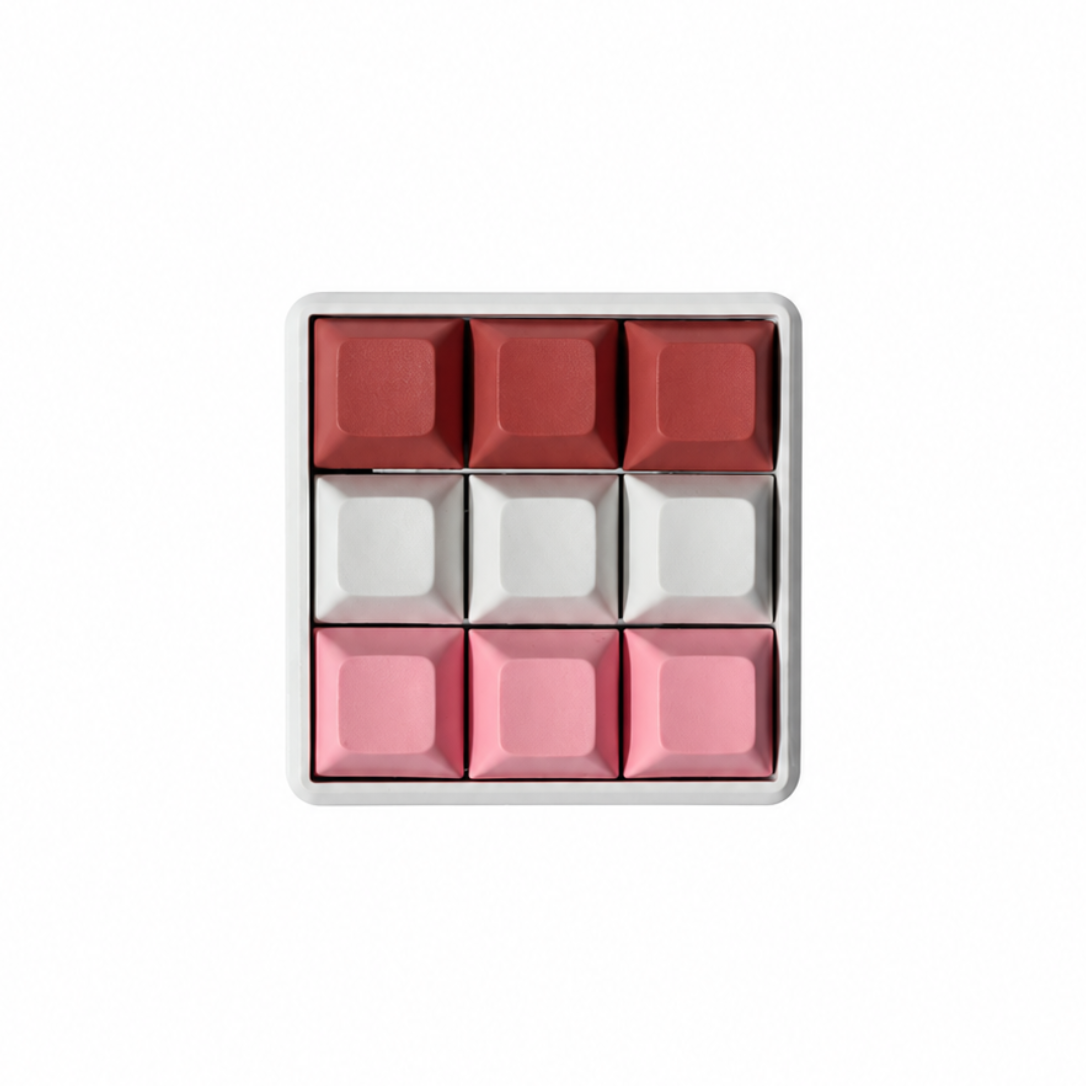 The Original 9-key square fidget with terracotta, white, and pink keycaps on a white base.